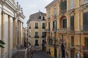 Una calle estrecha bordeada por edificios históricos con balcones y una escalera central que conduce a un piso superior.