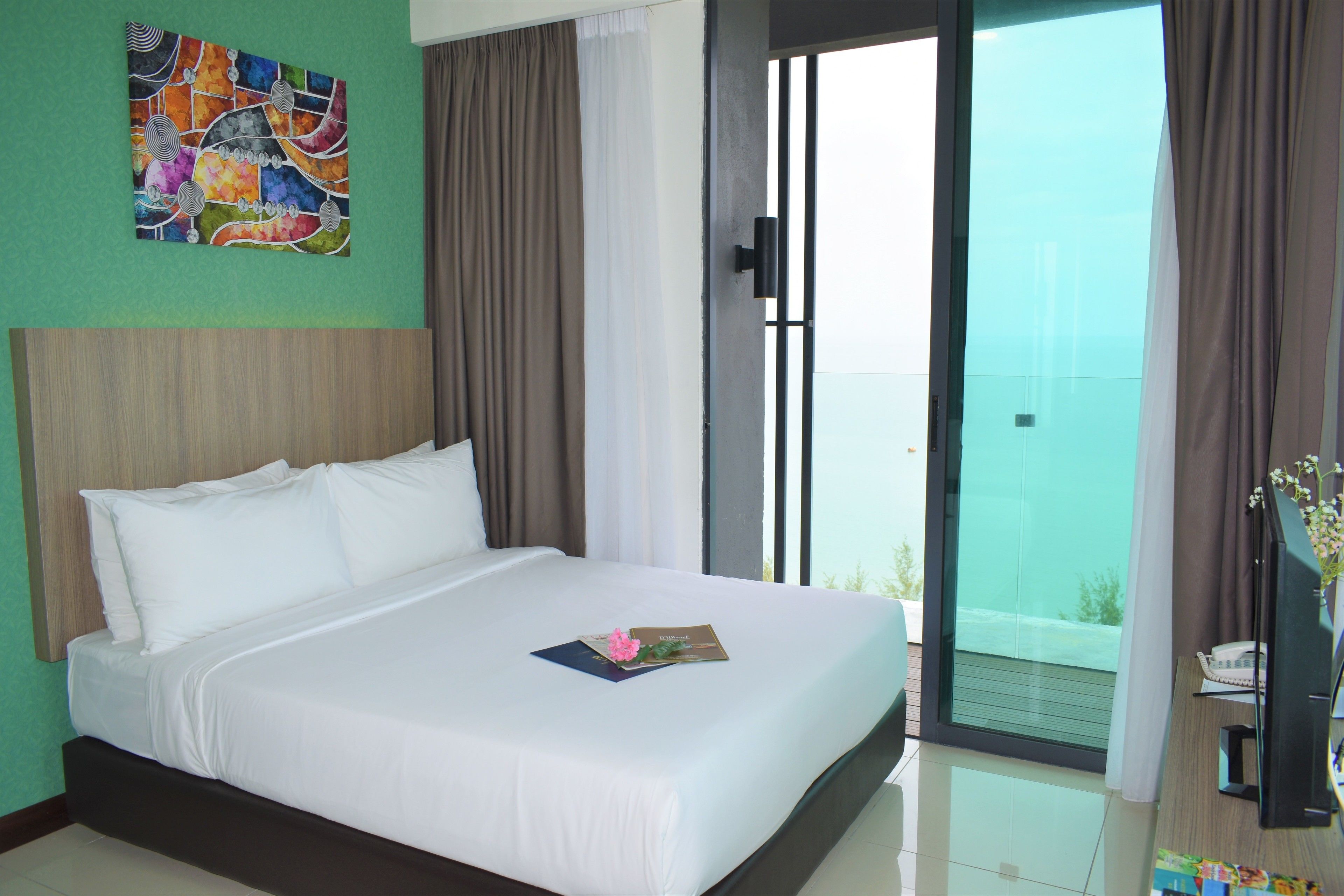 Una habitación de hotel con una cama grande, vista al exterior y un cuadro en la pared.