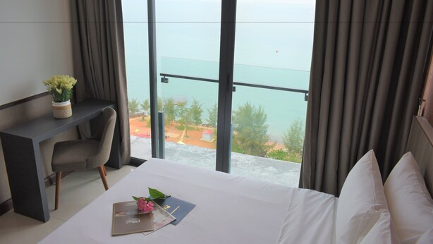 A hotel room with a bed, a desk, and a view of the sea. - D'Wharf Hotel & Serviced Residence (Port Dickson)