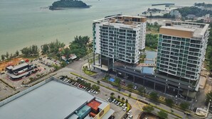 A modern hotel with multiple floors, a parking lot, and a view of the sea and a small island. - D'Wharf Hotel & Serviced Residence (Port Dickson)