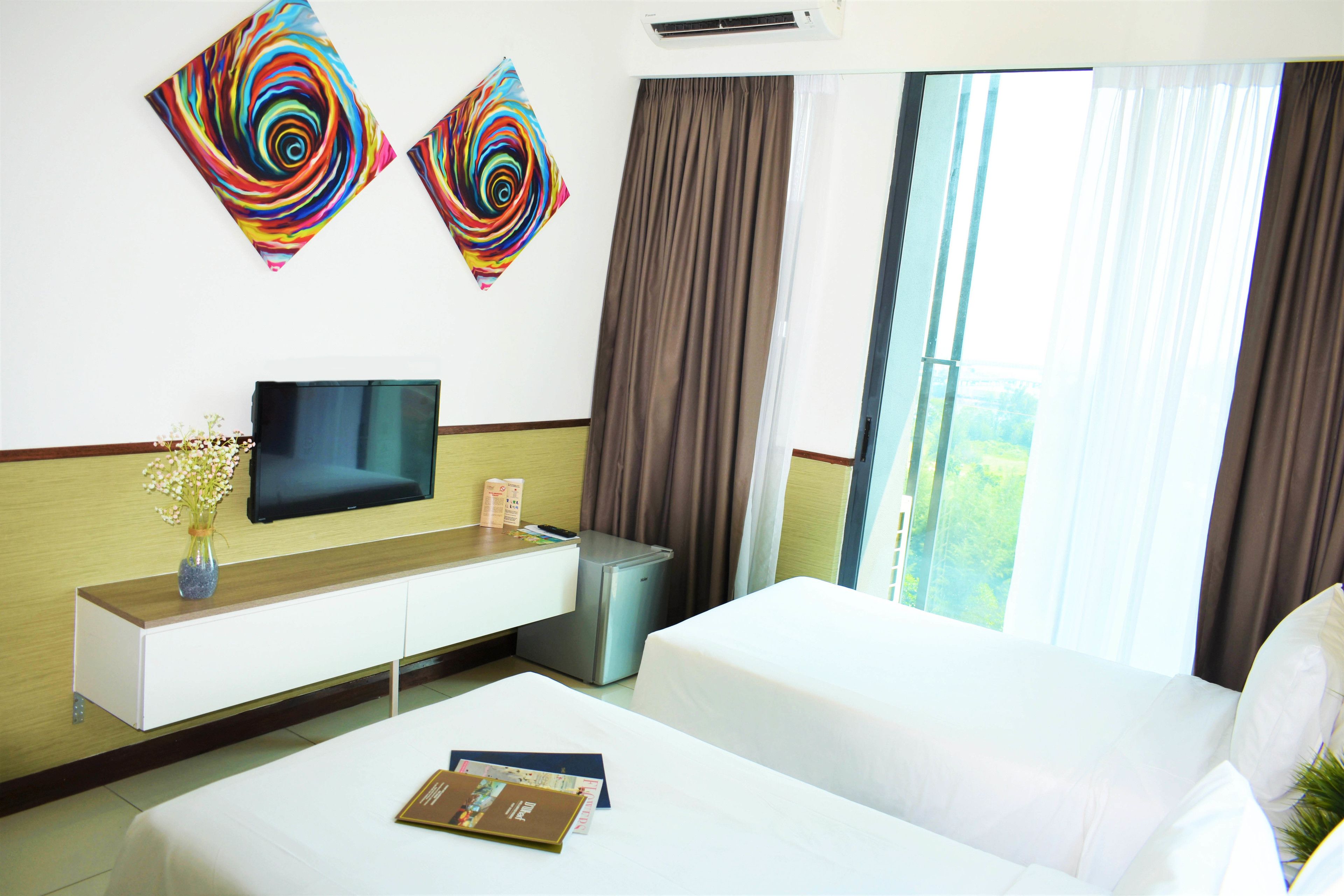 A hotel room with a bed, a bedside table with a vase of flowers, a TV, and two abstract paintings on the wall.