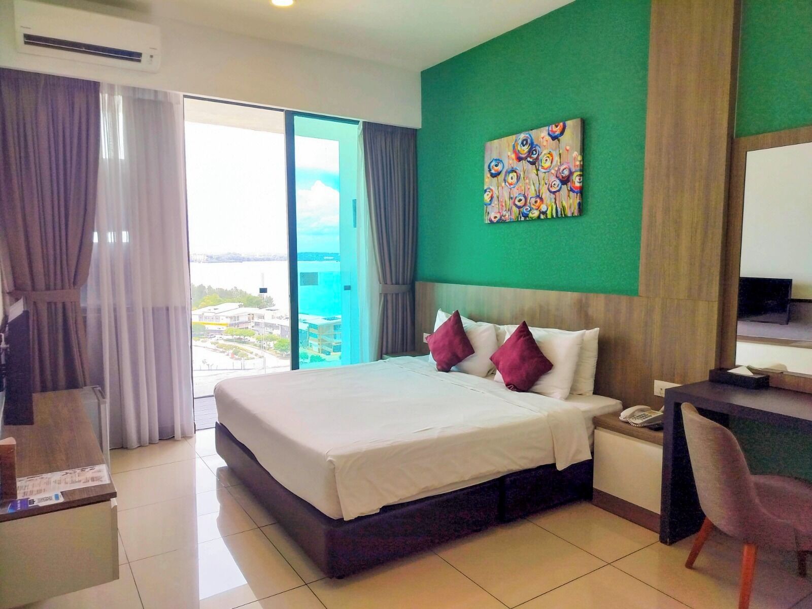 A hotel room with a large bed, a desk, and a view of the city.