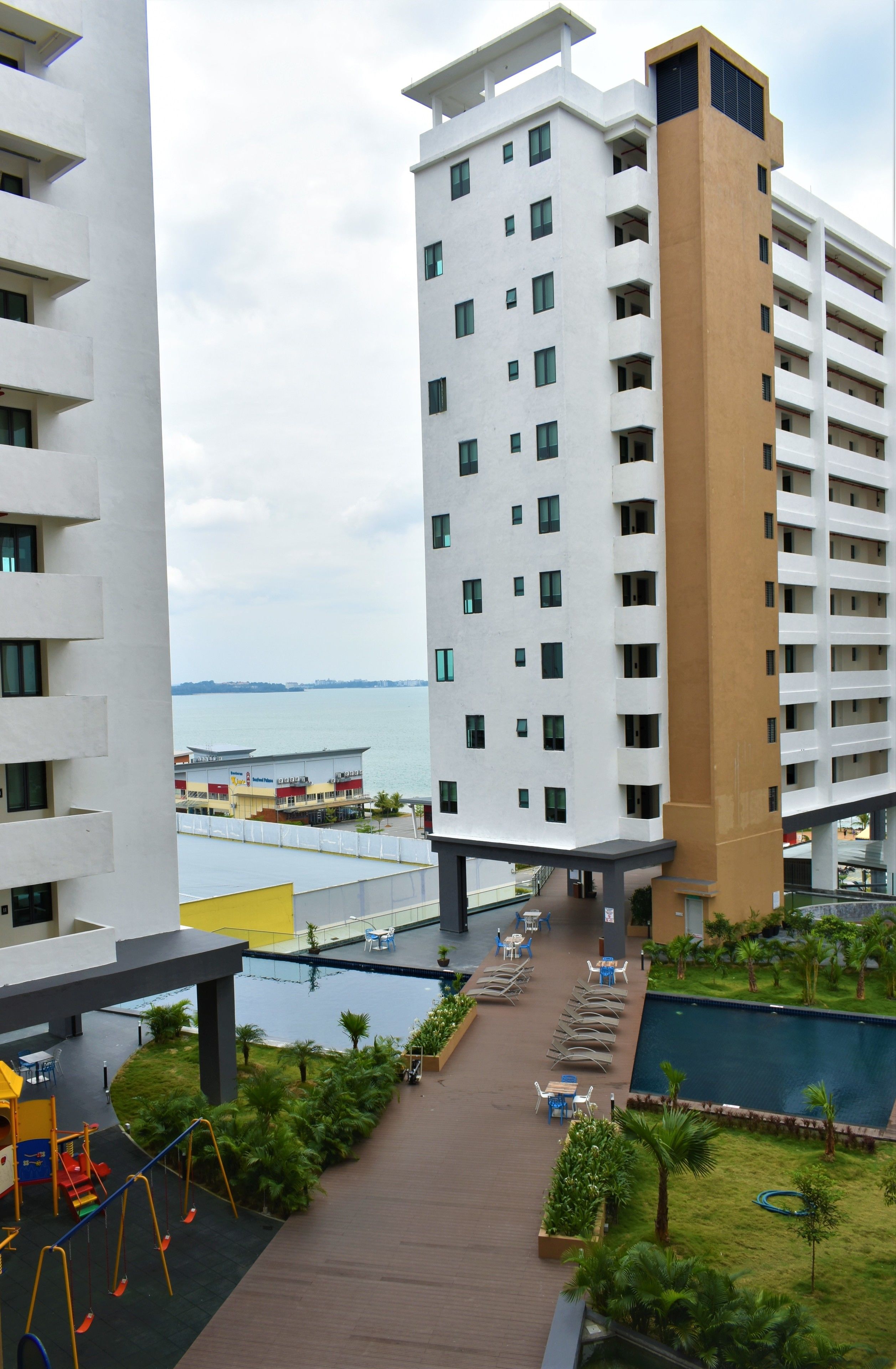 A high-rise hotel with a swimming pool, outdoor seating, and a view of the water.