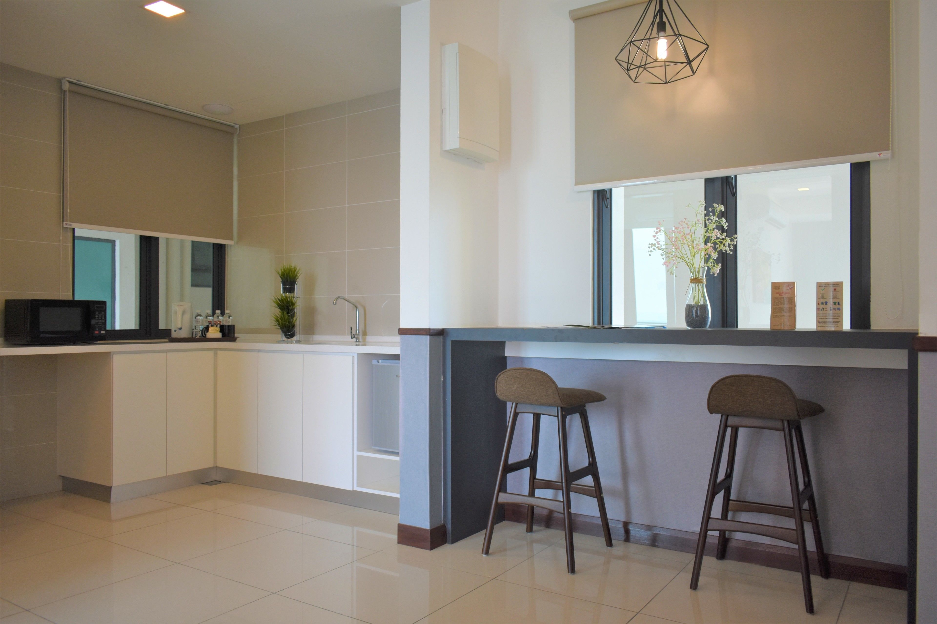 A modern kitchen with a large island, bar stools, a microwave, and a potted plant.