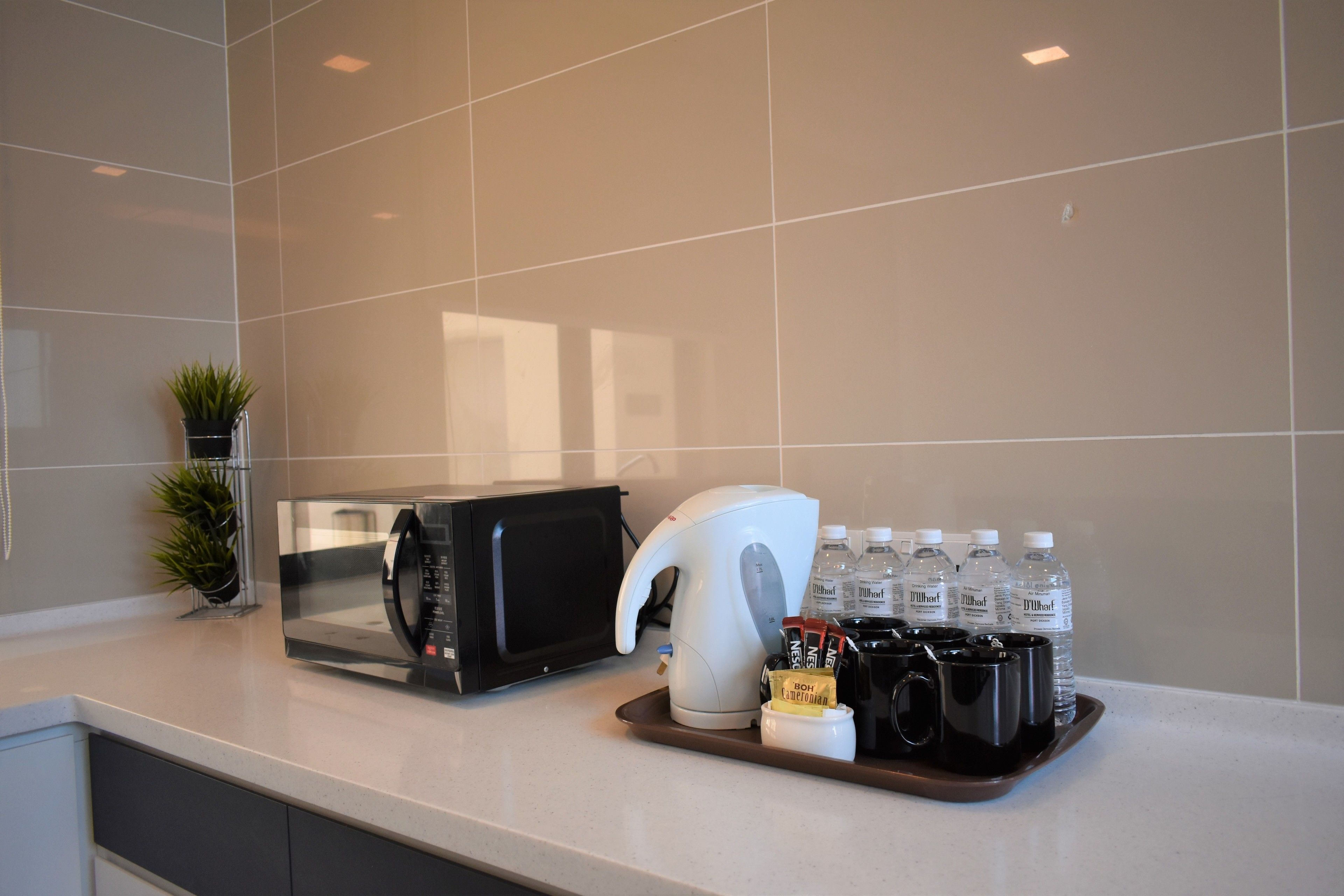 Una encimera de cocina con microondas, cafetera y agua embotellada.
