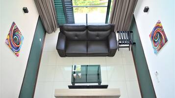 A modern living room with a sofa, glass coffee table, and artwork on the walls.