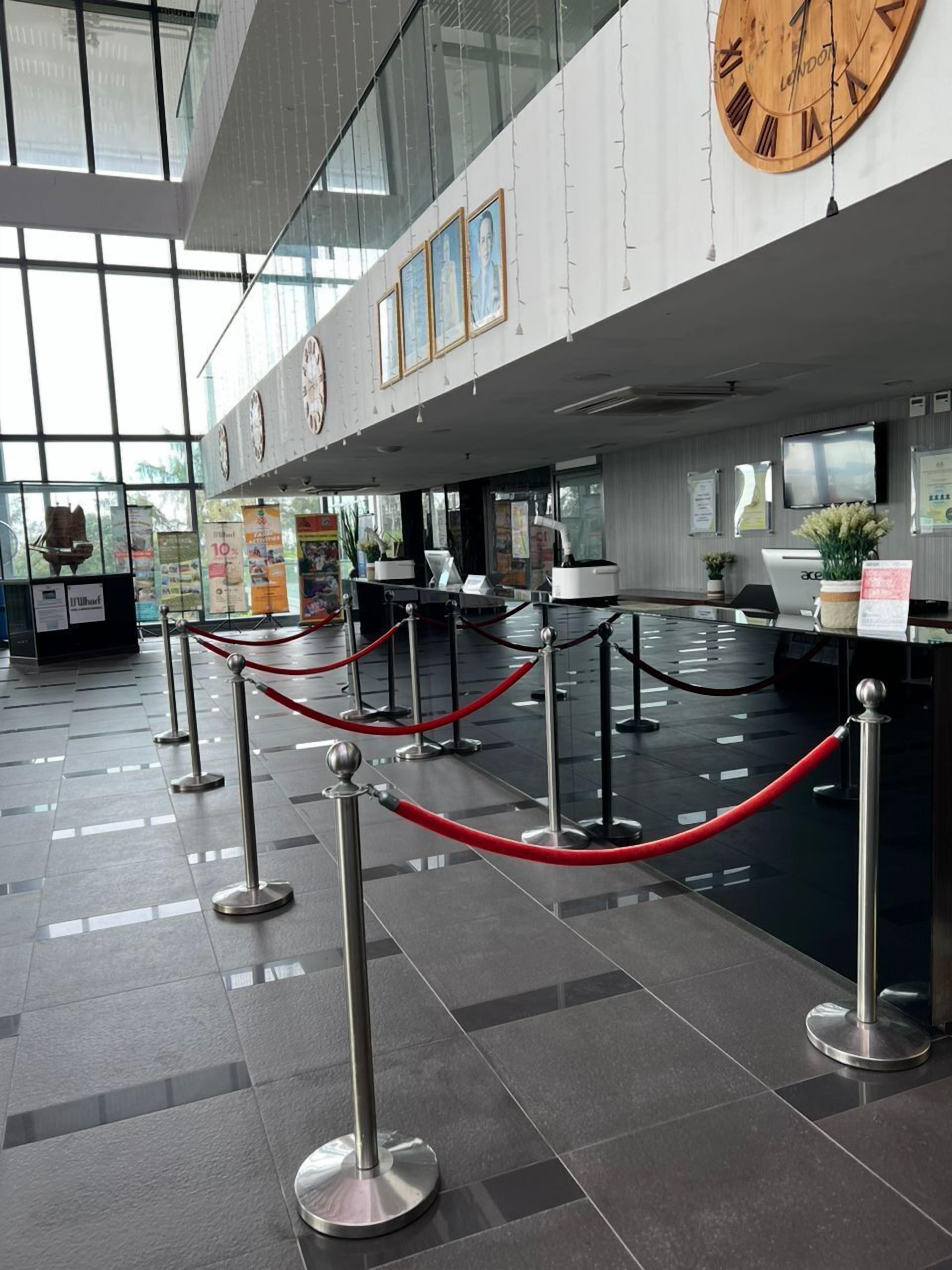 A modern reception area with a check-in counter, multiple clocks, and a glass partition.