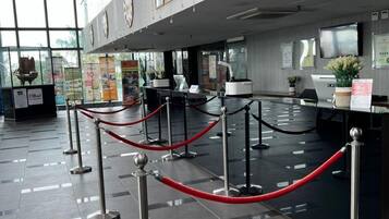 A modern reception area with a check-in counter, multiple clocks, and a glass partition.