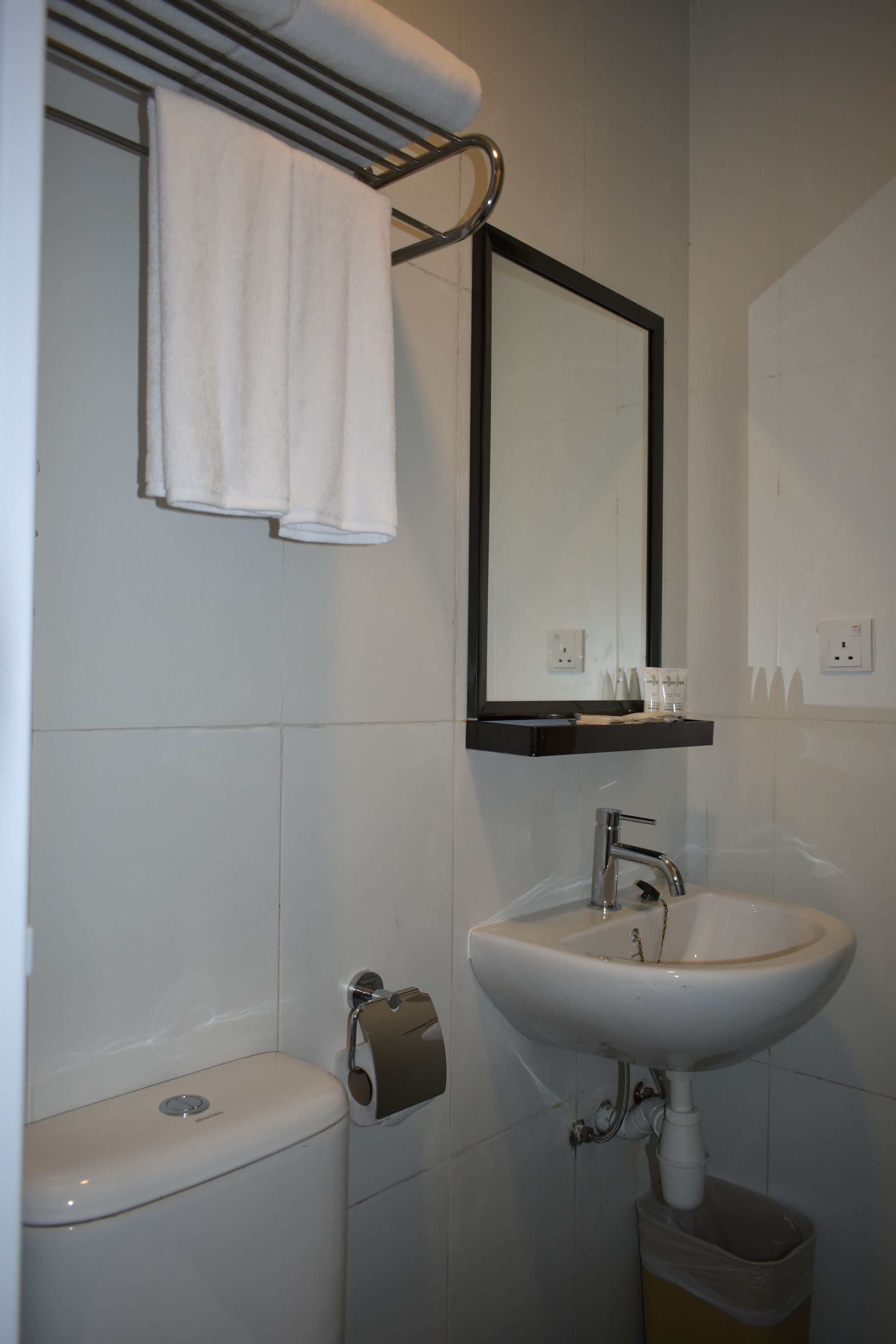 A bathroom with a white sink, a mirror, a towel rack, and a toilet.