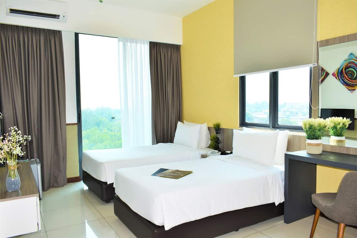 A hotel room with two beds, a desk, a chair, a TV, and a window with curtains.