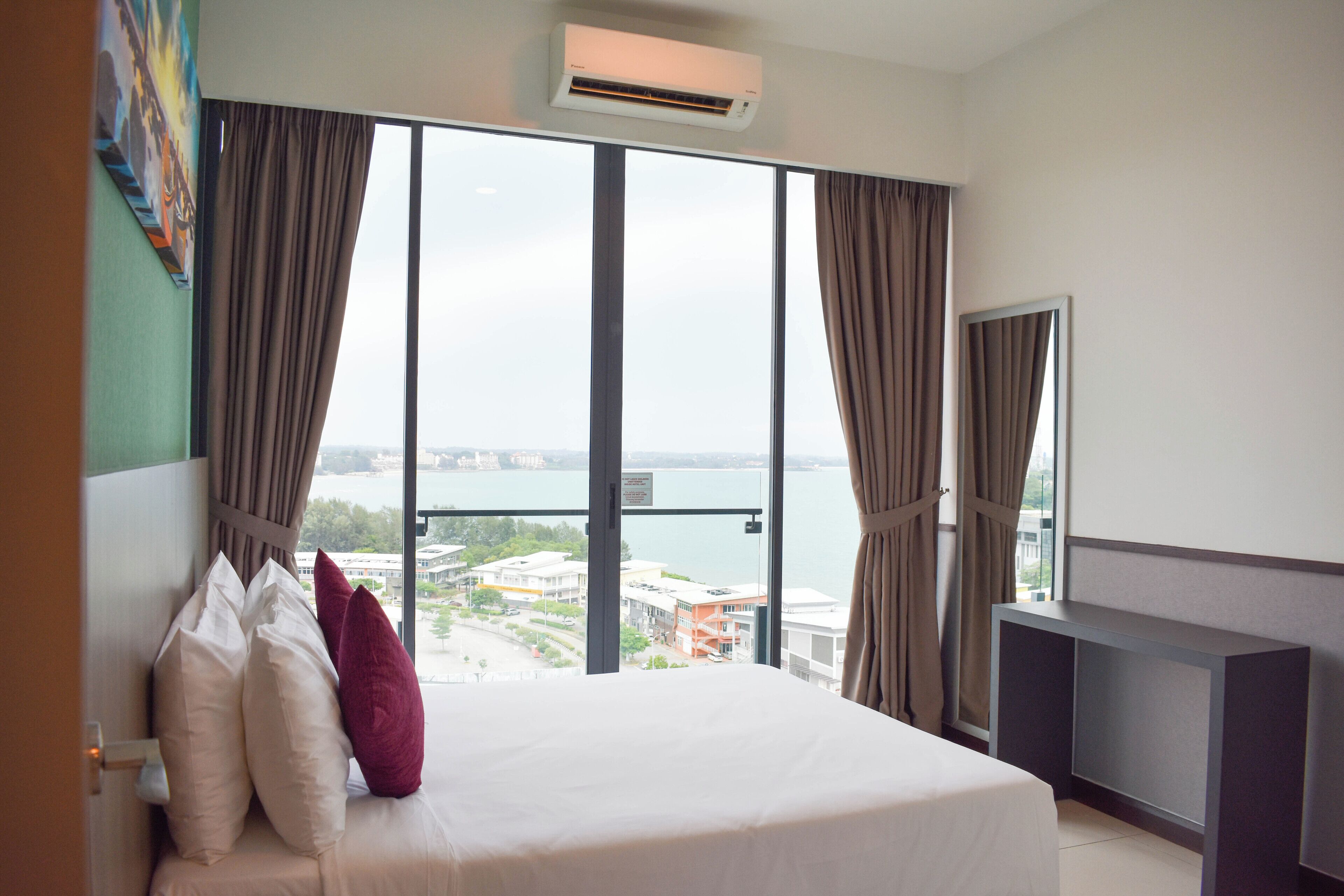 Quarto de hotel com uma cama grande, vista para a cidade e uma varanda.