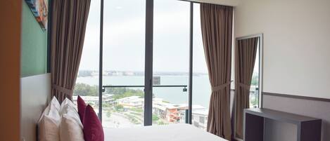 Habitación de hotel con una cama grande, vistas de la ciudad y un balcón.
