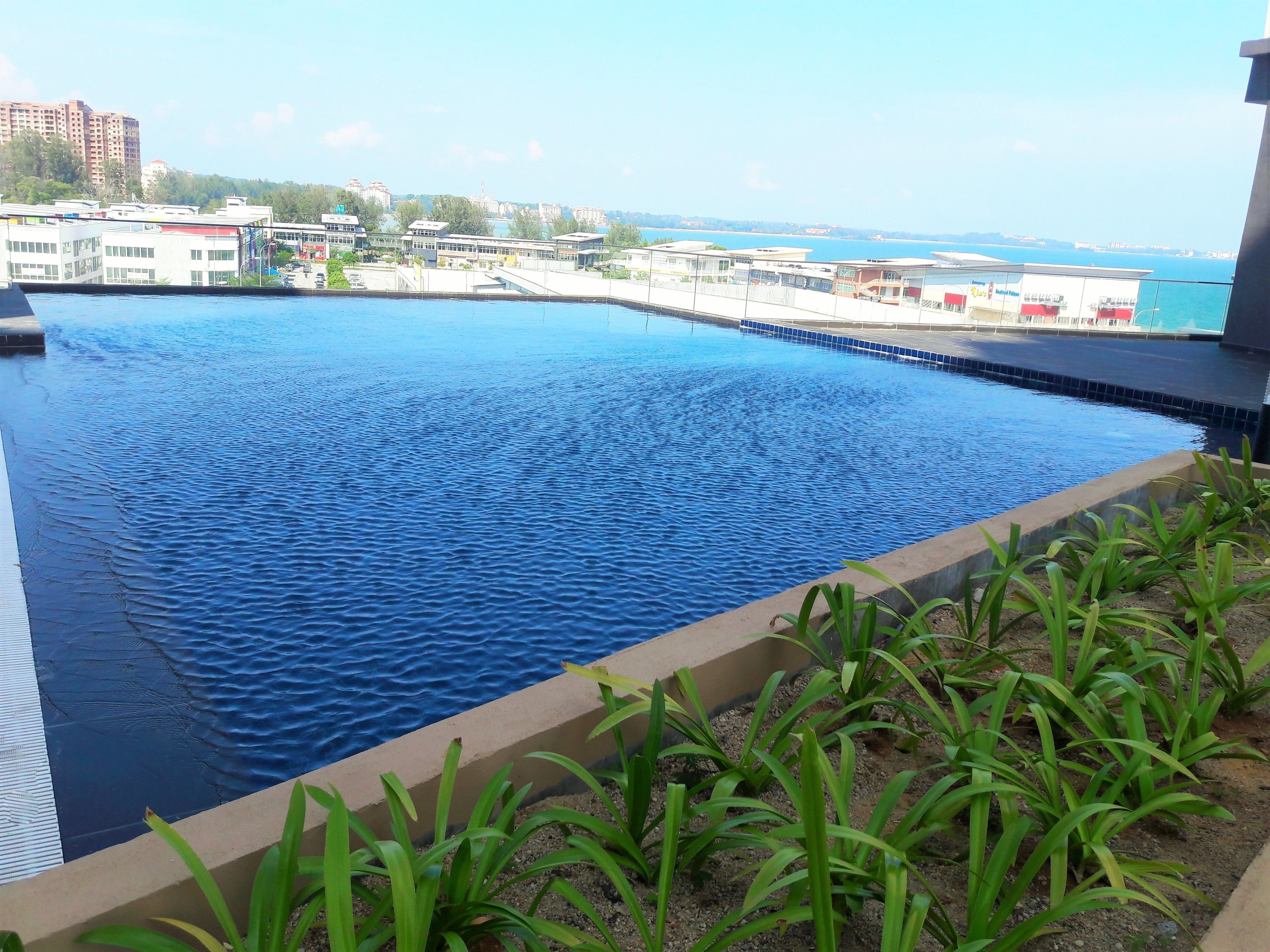 A swimming pool with a view of buildings and a distant shoreline.