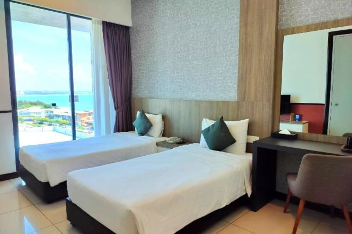 A hotel room with two beds, a desk, and a chair.