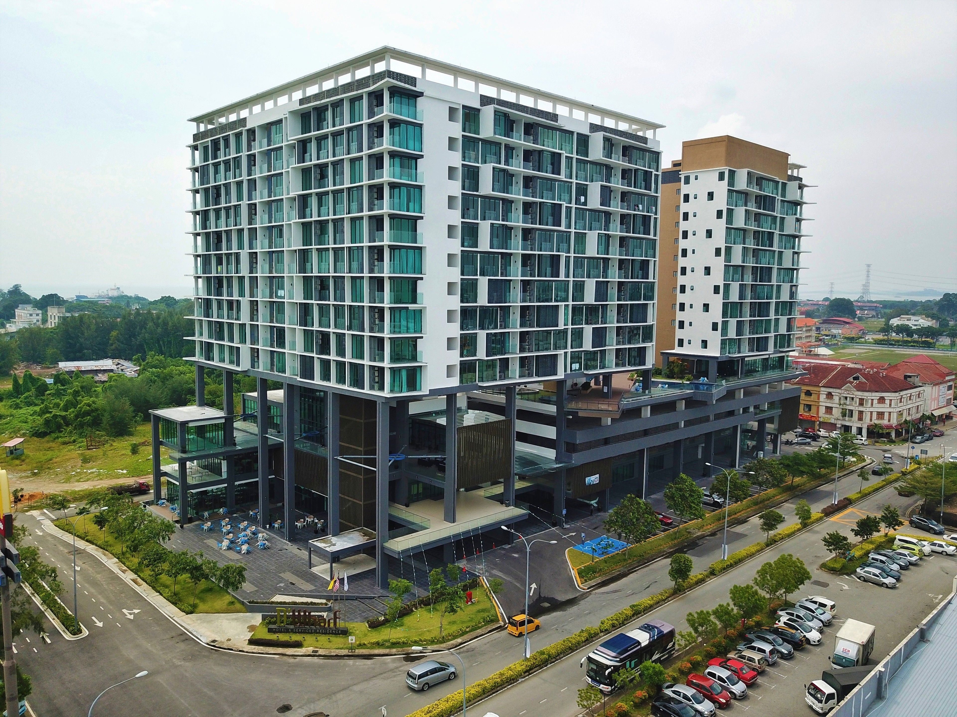 A modern hotel with multiple floors, large windows, and a rooftop terrace.