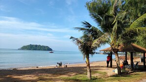 A beach with a small island in the distance, a covered seating area, and a few people near the water. - D'Wharf Hotel & Serviced Residence (Port Dickson)