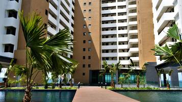 Un hotel moderno con area piscina, palme e vista sull'oceano.