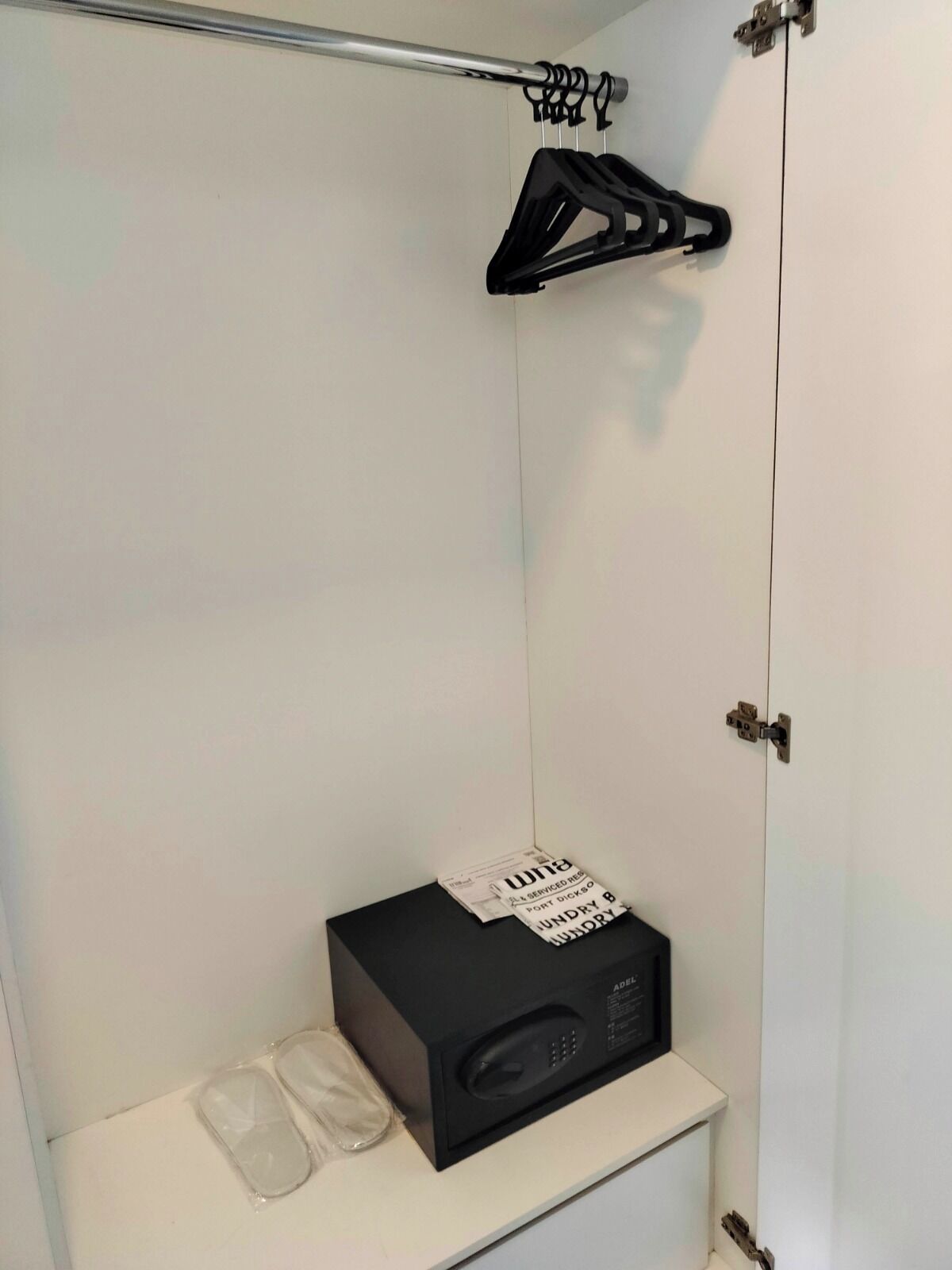 Une salle de bain avec un lavabo blanc, une radio noire et un porte-vêtements suspendu.
