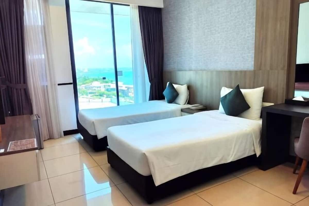 A hotel room with two beds, a desk, a chair, a nightstand, and a large window with a view.