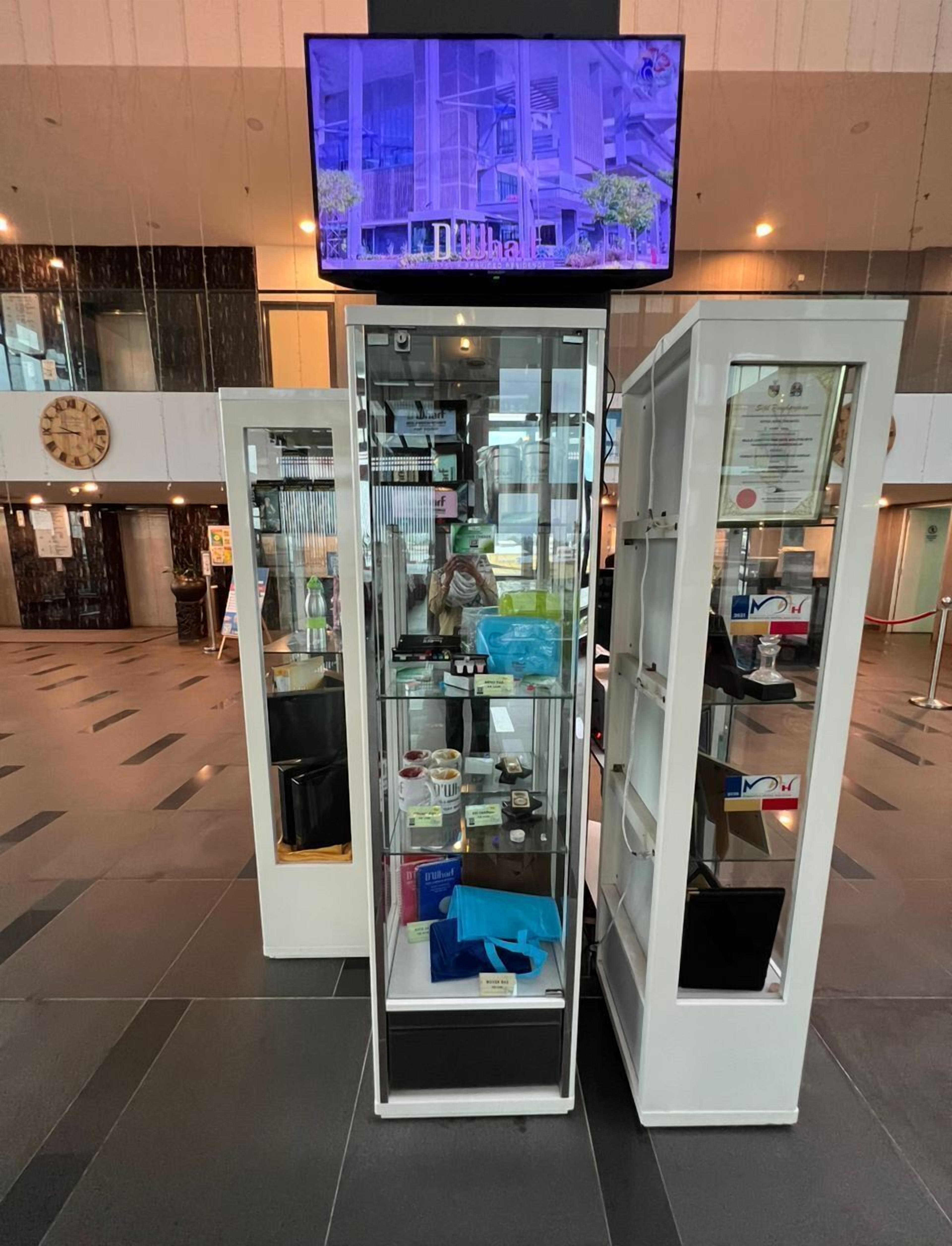En modern entréhall med ett glasmontr som innehåller olika föremål, en klocka och en tv som är monterad i taket.