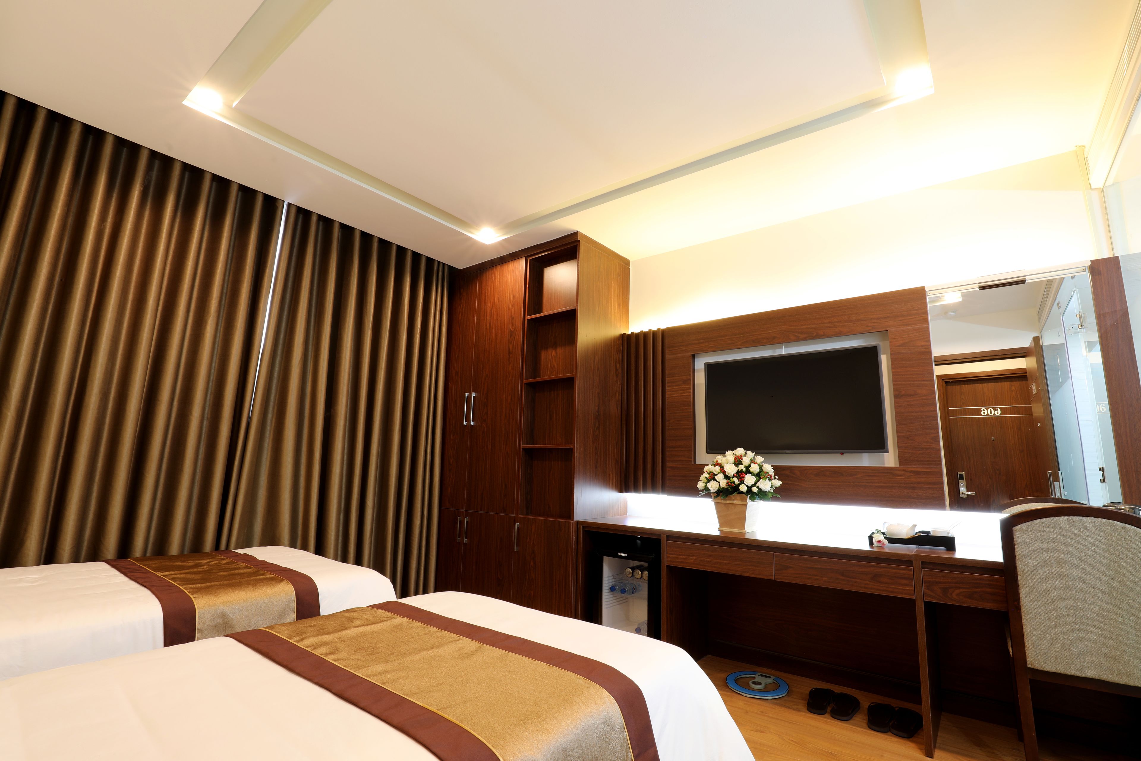 A hotel room with two beds, a desk, a mirror, and a TV.