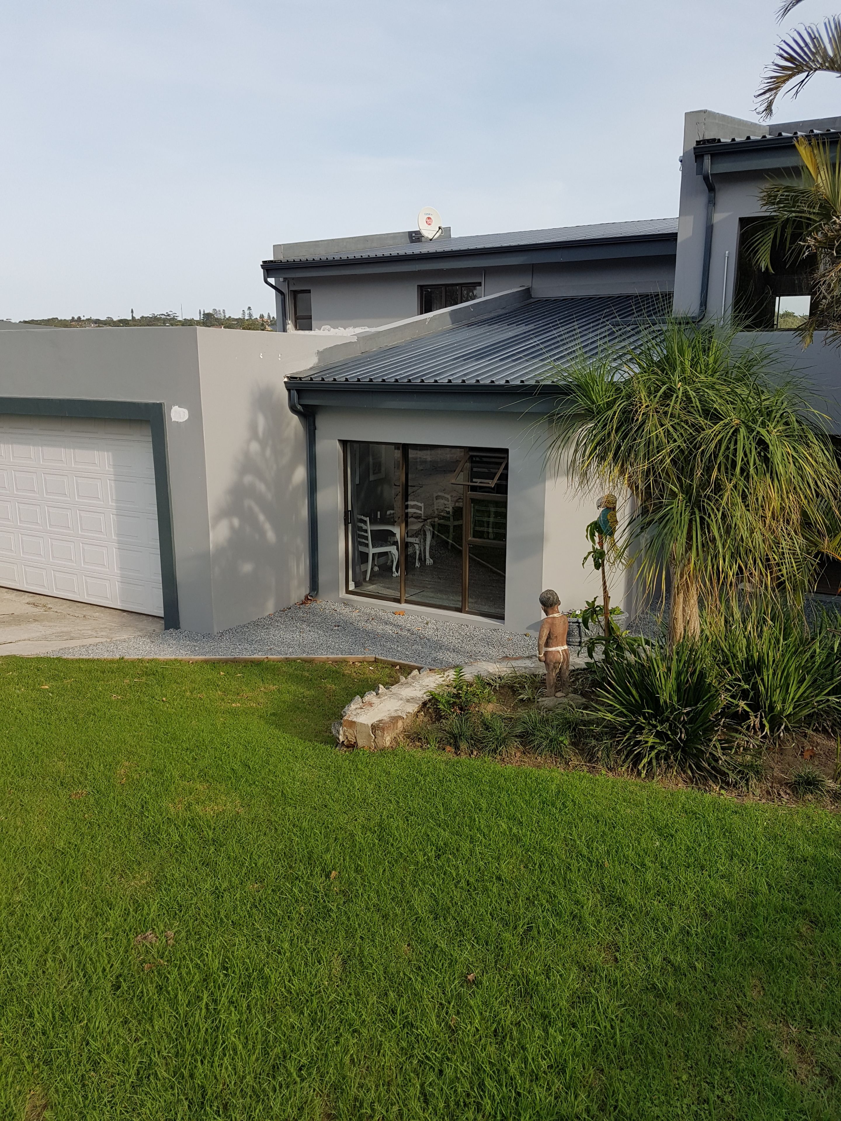 A modern house with a garage, a large glass door, and a well-maintained lawn.