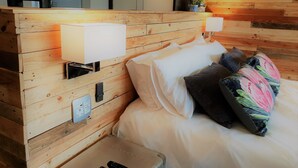 A wooden headboard with a bedside table, a lamp, and a remote control. - Riverview Guesthouse (East London)