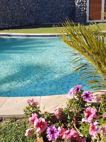 Una piscina al aire libre, sombrillas, sillones reclinables de piscina