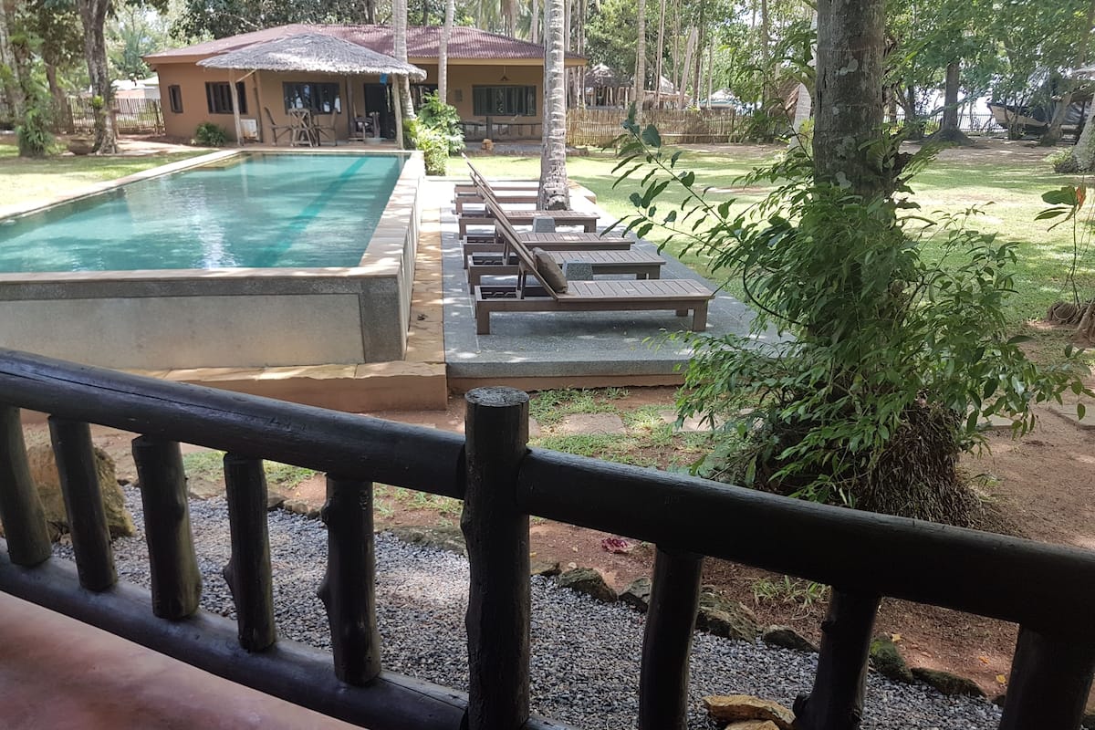 Área da piscina com espreguiçadeiras e um edifício ao fundo.