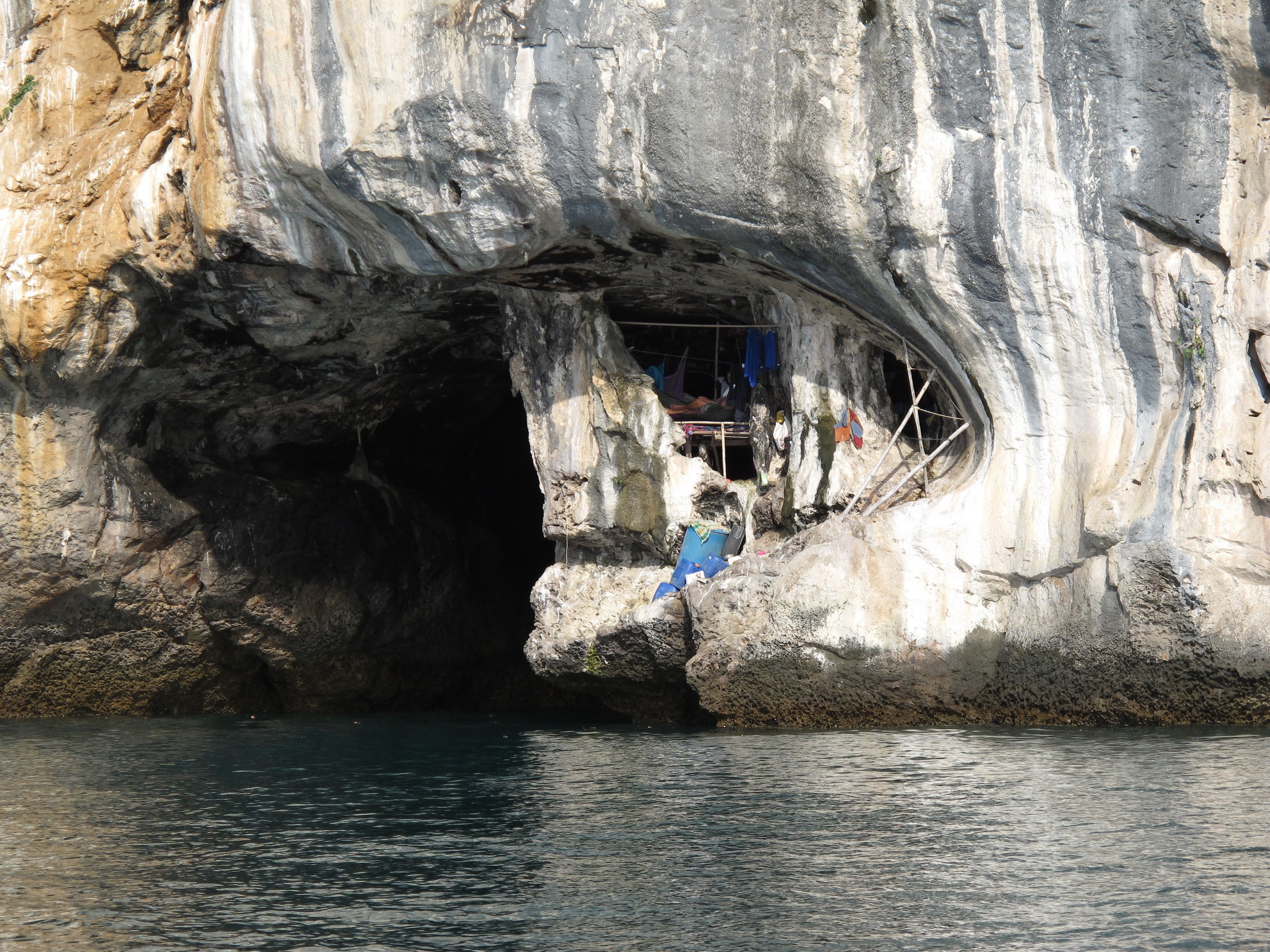 A cave entrance with a small shelter inside, surrounded by rocky walls.