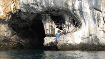 A cave entrance with a small shelter inside, surrounded by rocky walls.