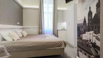 Ein Hotelzimmer mit Bett, Schreibtisch, Stuhl, einem Fenster mit Vorhängen und einem an der Wand montierten Fernseher.