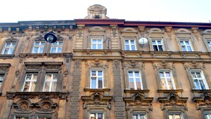 Un edificio histórico con detalles arquitectónicos ornamentales, múltiples ventanas y un reloj destacado.