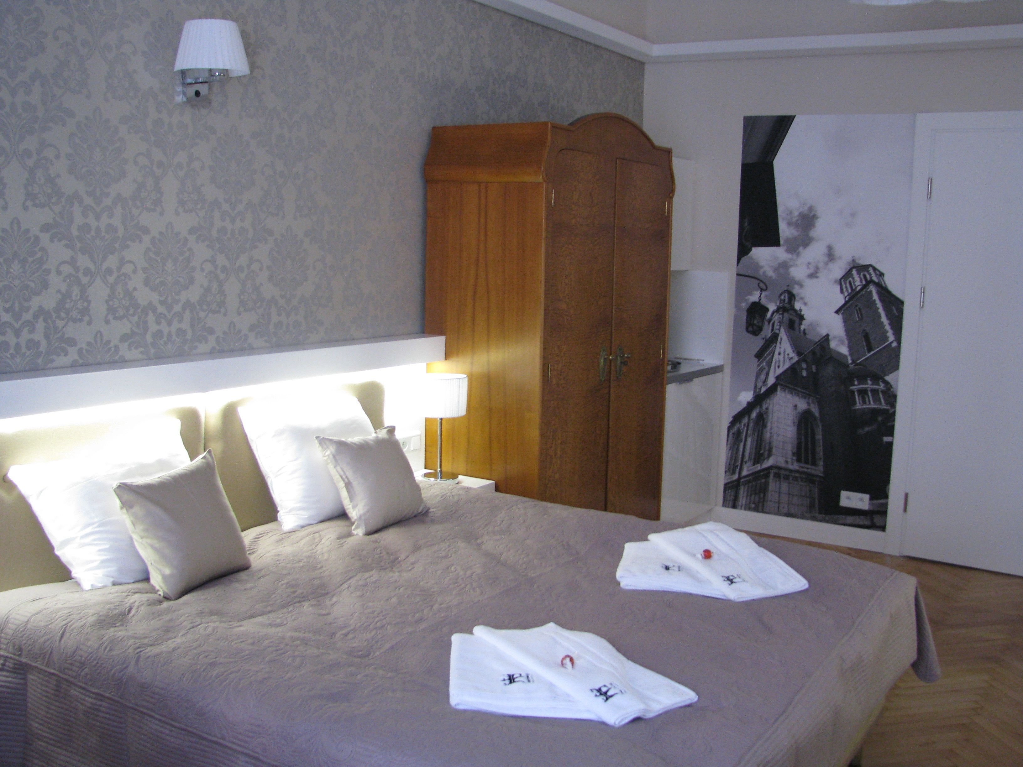 A hotel room with a large bed, a wardrobe, and a wall-mounted lamp.