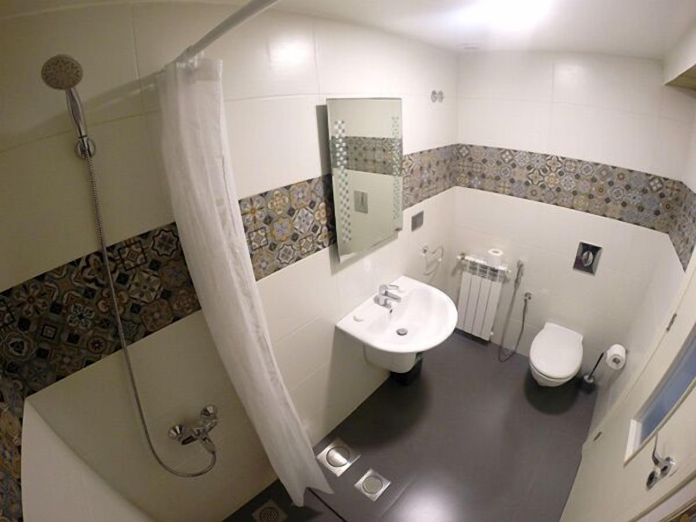 A bathroom with a shower, toilet, sink, and a mirror.