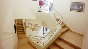 Eine Treppe mit weißen Geländern und beigen Stufen, die zu einer oberen Etage führt.