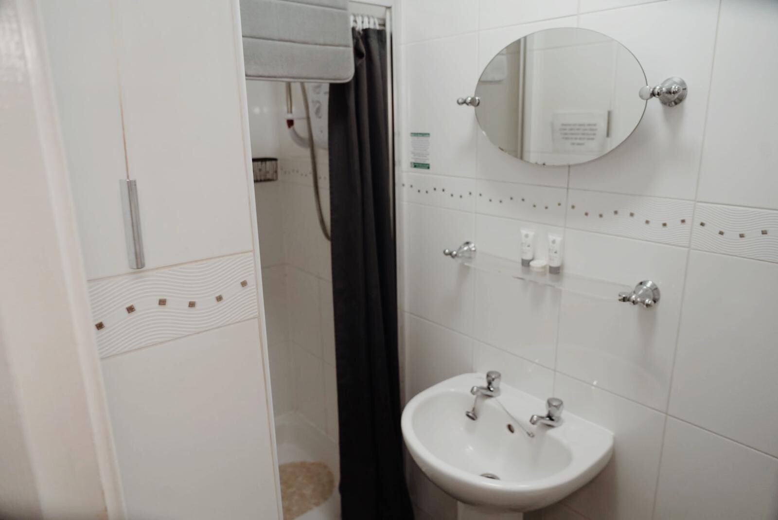 A bathroom with a white sink, a mirror, and a shower area.