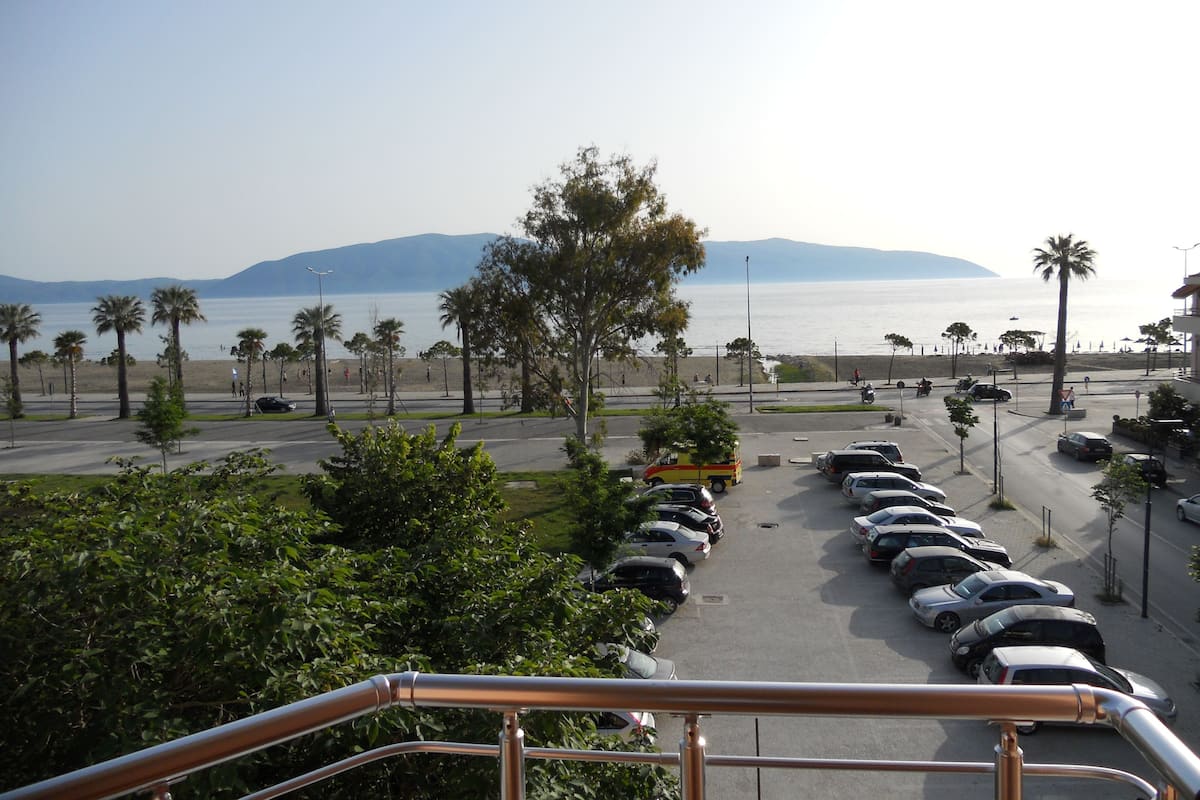 Un parking rempli de voitures, avec une vue sur la plage et les montagnes au loin.