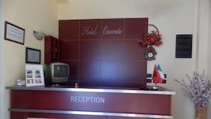 Un mostrador de recepción con un cartel que dice "Hotel Onorato" y un certificado enmarcado en la pared.