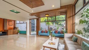Een moderne hotellobby met een houten plafond, grote ramen, een receptiebalie en zitgedeeltes.