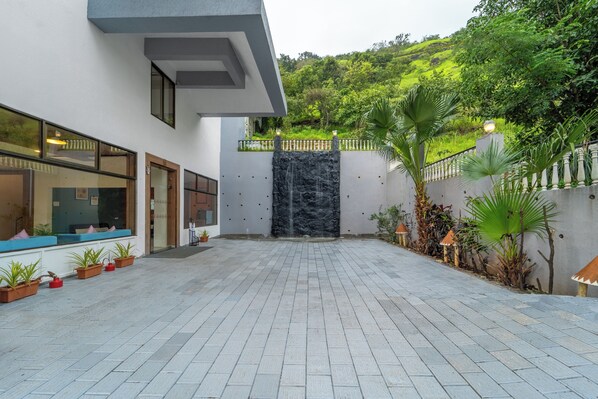 Un patio con cascada, plantas en macetas y un edificio con ventanales grandes.