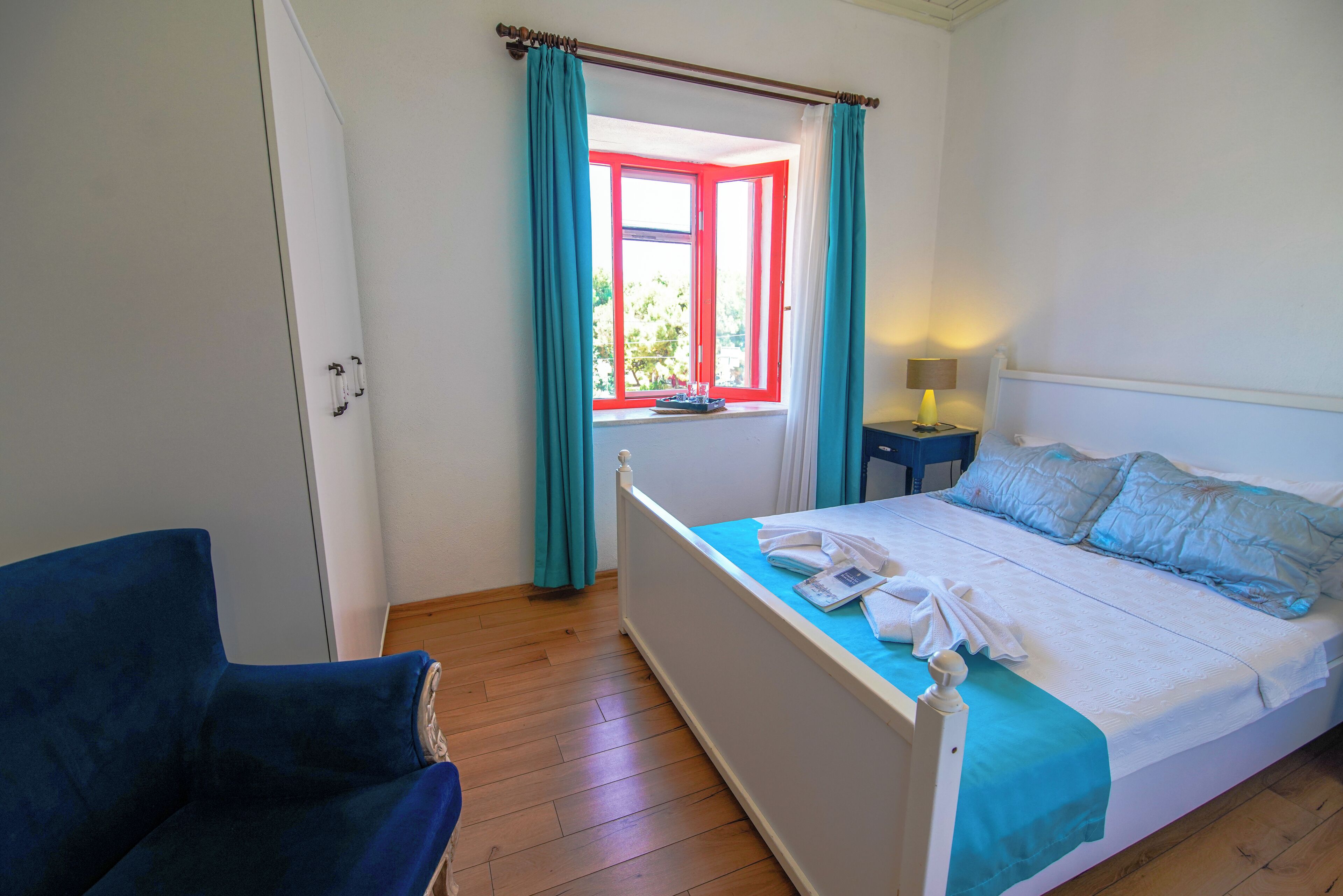 Une chambre à coucher avec un lit, une table de chevet, une chaise et une fenêtre avec des rideaux.
