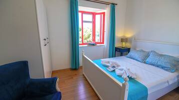 Une chambre à coucher avec un lit, une table de chevet, une chaise et une fenêtre avec des rideaux.