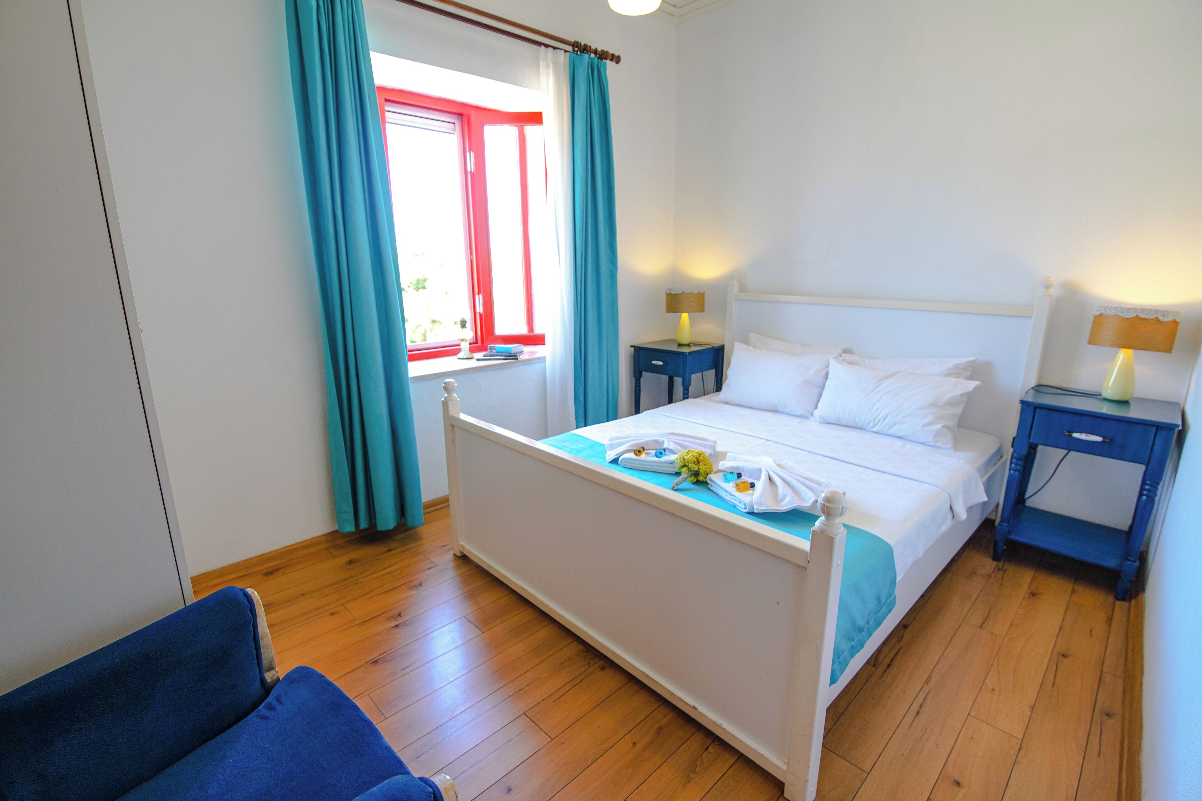 A bedroom with a bed, two bedside tables, a chair, and a window with curtains.