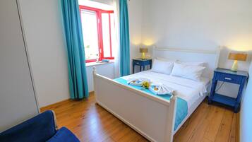 A bedroom with a bed, two bedside tables, a chair, and a window with curtains.