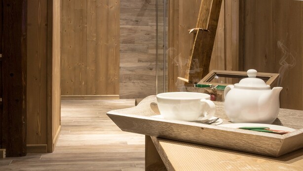 A wooden interior with a table displaying a teapot and cups. - Hotel Riva Sport & Wellness (Vione)