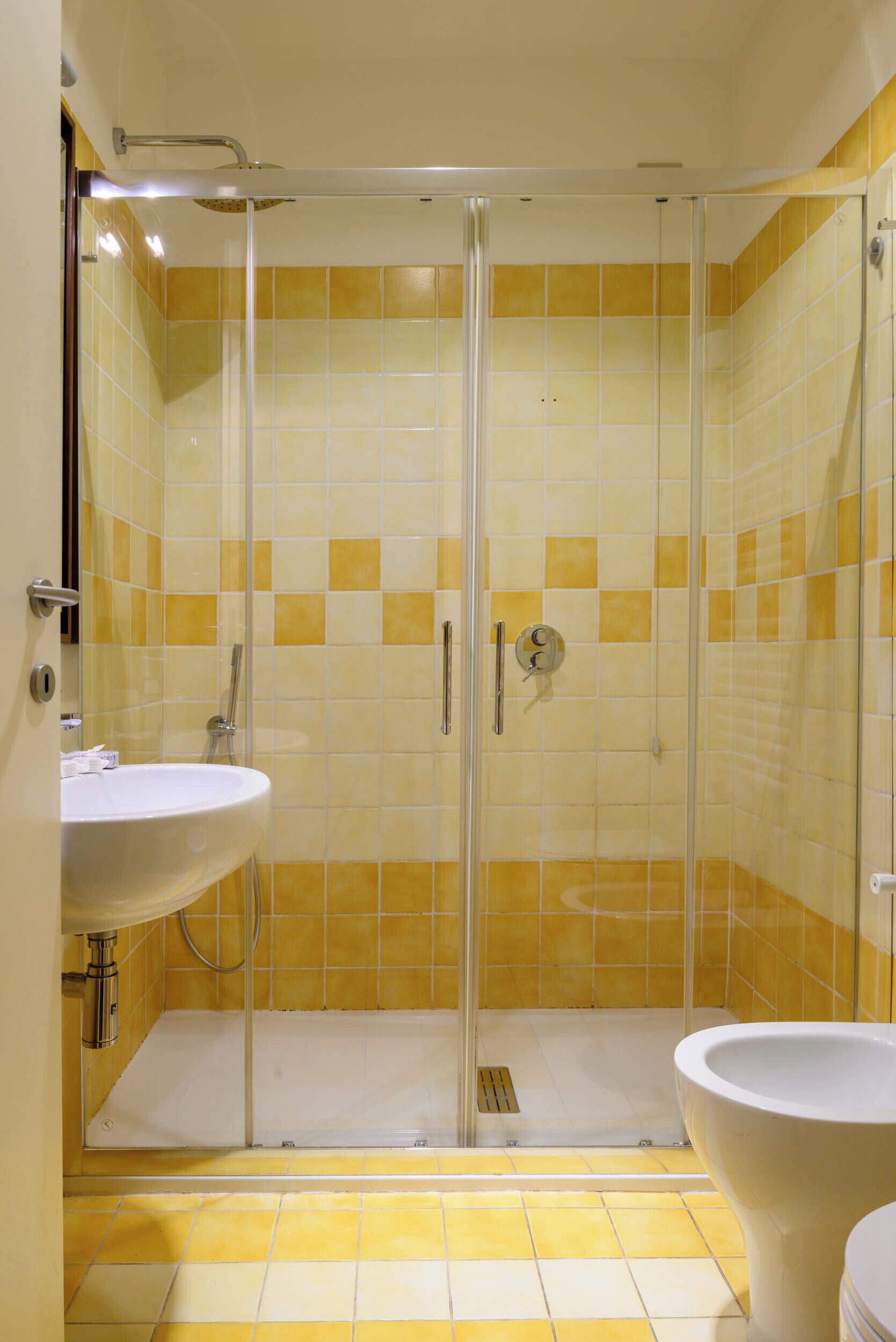 A bathroom with a glass-enclosed shower, a sink, and a toilet.