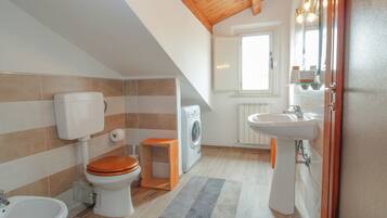 Une petite salle de bain comprenant des toilettes, un bidet, un lavabo et un lave-linge.