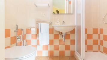 A bathroom with a toilet, sink, and shower.