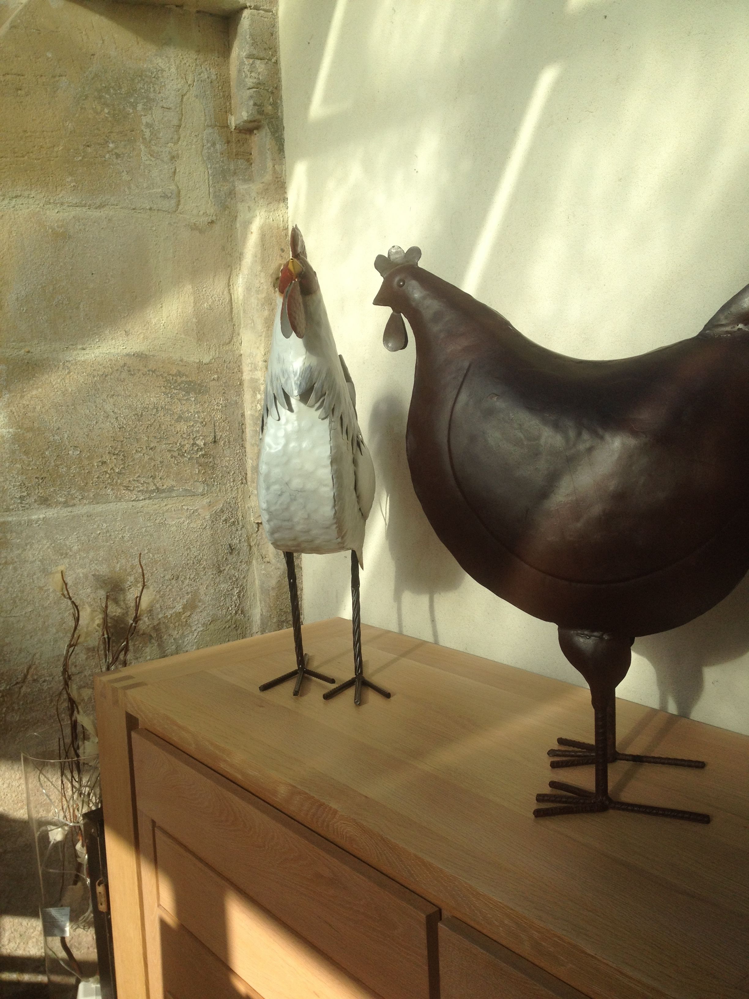 A wooden table with two decorative chickens on it.